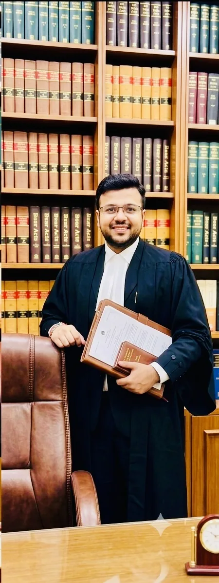 Advocate Aayush Agarwal standing beside a leather chair in front of shelves of law reports, holding case files and a book